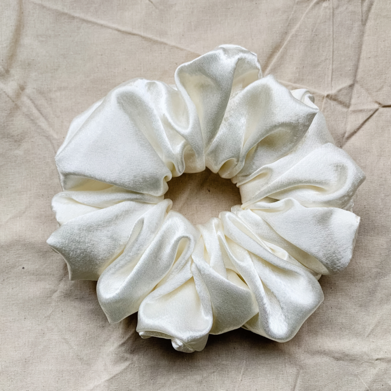 Cream Cloud XL scrunchie in ivory, made from luxurious charmeuse silk. Four times the size of the chunky scrunchie, this oversized scrunchie offers an extravagant, voluminous look with a smooth, glossy finish, perfect for making a bold statement or securing hair comfortably.