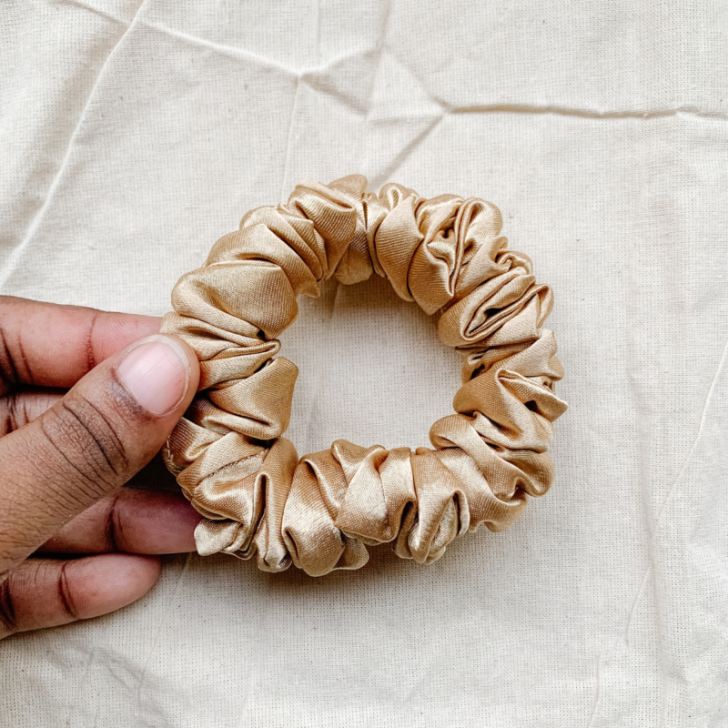 Golden Glow petite scrunchie made from luxe charmeuse satin. Oversized design, approximately twice the size of a standard scrunchie, with a smooth, glossy finish that adds a touch of elegance to any hairstyle.