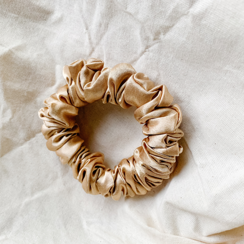 Golden Glow petite scrunchie made from luxe charmeuse satin. Oversized design, approximately twice the size of a standard scrunchie, with a smooth, glossy finish that adds a touch of elegance to any hairstyle.