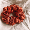 Sunset Glow terracotta chunky scrunchie made from luxe charmeuse satin. Oversized design, approximately twice the size of a standard scrunchie, with a smooth, glossy finish that adds a touch of elegance and volume to any hairstyle.