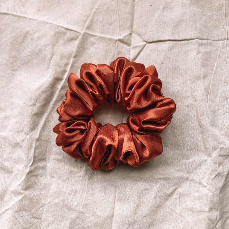 Sunset Glow terracotta chunky scrunchie made from luxe charmeuse satin. Oversized design, approximately twice the size of a standard scrunchie, with a smooth, glossy finish that adds a touch of elegance and volume to any hairstyle.