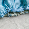 Blueberry Latte reversible silk bonnet in baby blue and ivory . Made from smooth charmeuse silk, this bonnet features a comfortable elastic band for a secure fit, offering a soft, luxurious touch for protecting hair while sleeping or resting