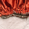 Dusky Sunseteversible silk bonnet in terracotta and cream. Made from smooth charmeuse silk, this bonnet features a comfortable elastic band for a secure fit, offering a soft, luxurious touch for protecting hair while sleeping or resting.