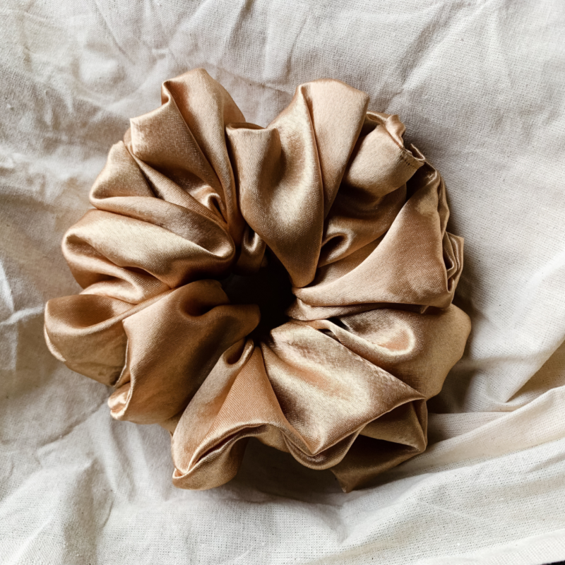 olden Glow XL scrunchie in yellow toned gold, made from luxurious charmeuse silk. Four times the size of the chunky scrunchie, this oversized scrunchie offers an extravagant, voluminous look with a smooth, glossy finish, perfect for making a bold statement or securing hair comfortably.