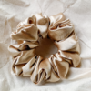 Golden Hour golden chunky scrunchie made from luxe charmeuse satin. Oversized design, approximately twice the size of a standard scrunchie, with a smooth, glossy finish that adds a touch of elegance and volume to any hairstyle.