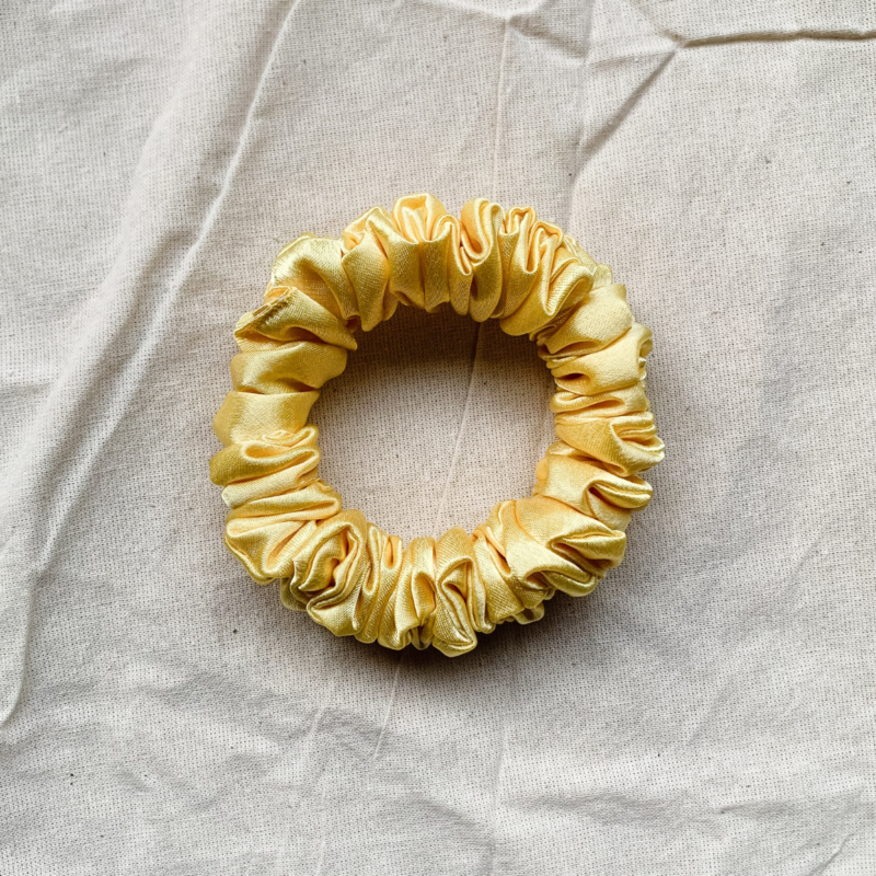 Lemonade yellow petite scrunchie made from luxe charmeuse satin. Oversized design, approximately twice the size of a standard scrunchie, with a smooth, glossy finish that adds a touch of elegance to any hairstyle.