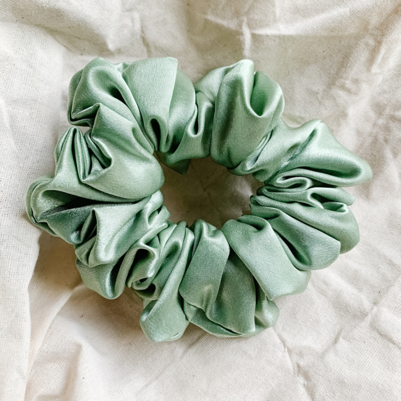 Matcha sage green chunky scrunchie made from luxe charmeuse satin. Oversized design, approximately twice the size of a standard scrunchie, with a smooth, glossy finish that adds a touch of elegance and volume to any hairstyle.