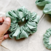 Matcha sage green chunky scrunchie made from luxe charmeuse satin. Oversized design, approximately twice the size of a standard scrunchie, with a smooth, glossy finish that adds a touch of elegance and volume to any hairstyle.