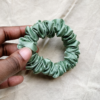 Matcha soft sage green petite scrunchie made from luxe charmeuse satin. Oversized design, approximately twice the size of a standard scrunchie, with a smooth, glossy finish that adds a touch of elegance to any hairstyle.