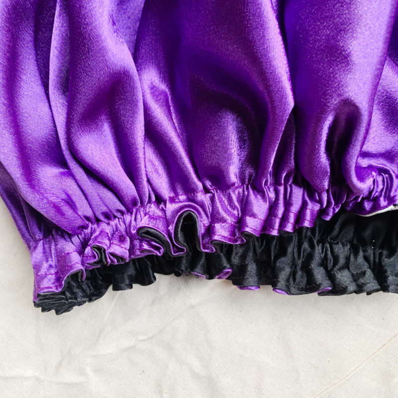 Midnight Amethyst reversible silk bonnet in purple and black. Made from smooth charmeuse silk, this bonnet features a comfortable elastic band for a secure fit, offering a soft, luxurious touch for protecting hair while sleeping or resting.