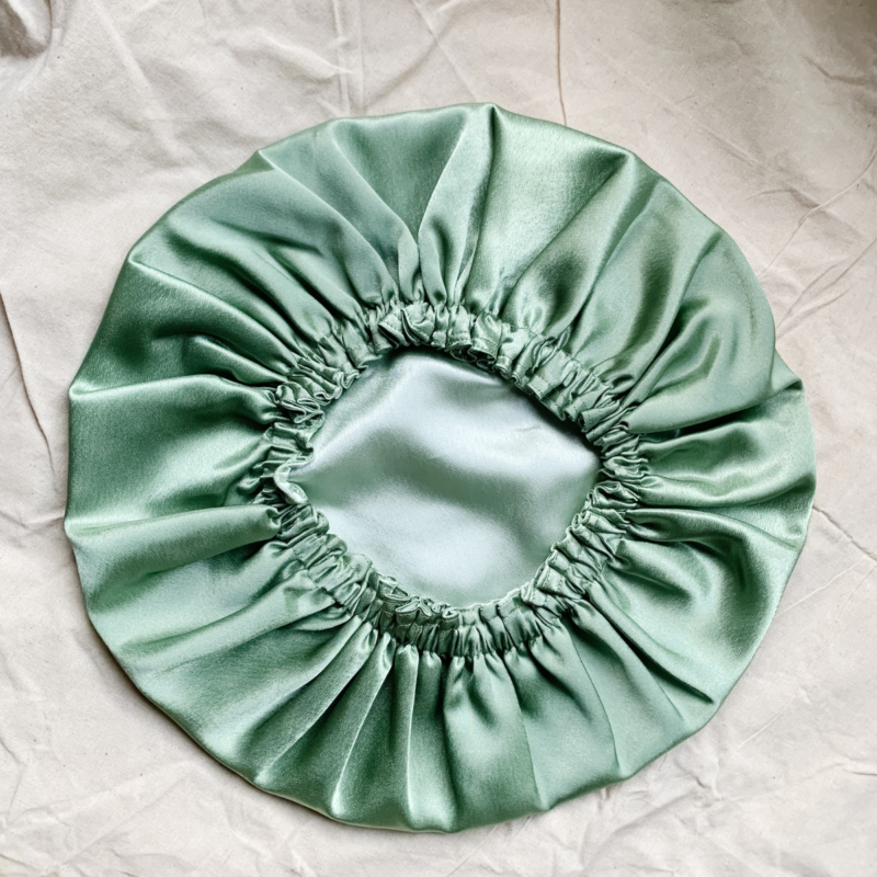 Minted Matcha Latte reversible silk bonnet in frosted mint green and sage green . Made from smooth charmeuse silk, this bonnet features a comfortable elastic band for a secure fit, offering a soft, luxurious touch for protecting hair while sleeping or resting.