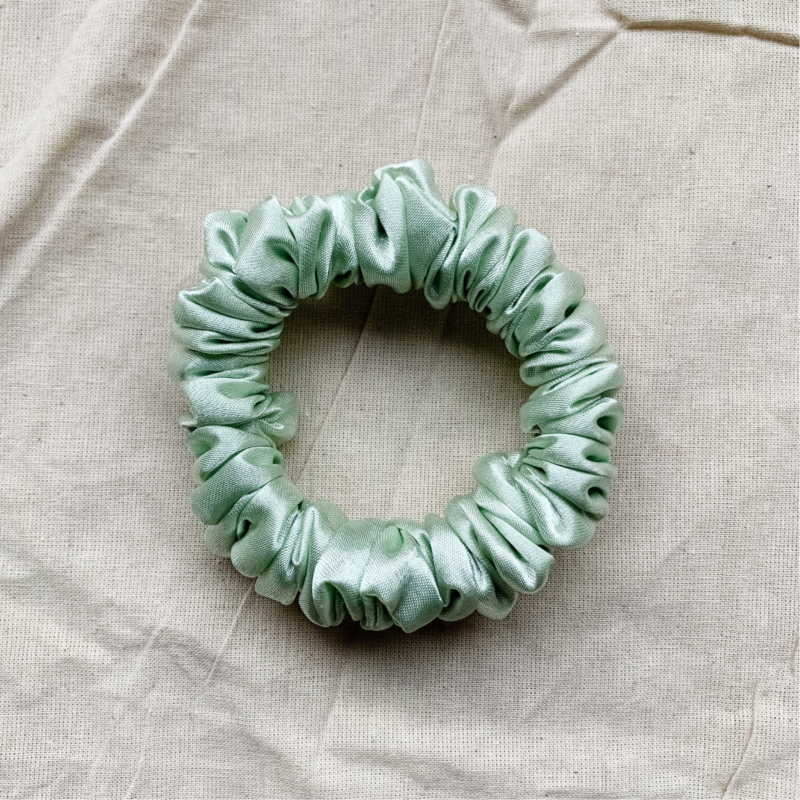 Minted Petite dusty mint green scrunchie made from luxe charmeuse satin. Oversized design, approximately twice the size of a standard scrunchie, with a smooth, glossy finish that adds a touch of elegance to any hairstyle.