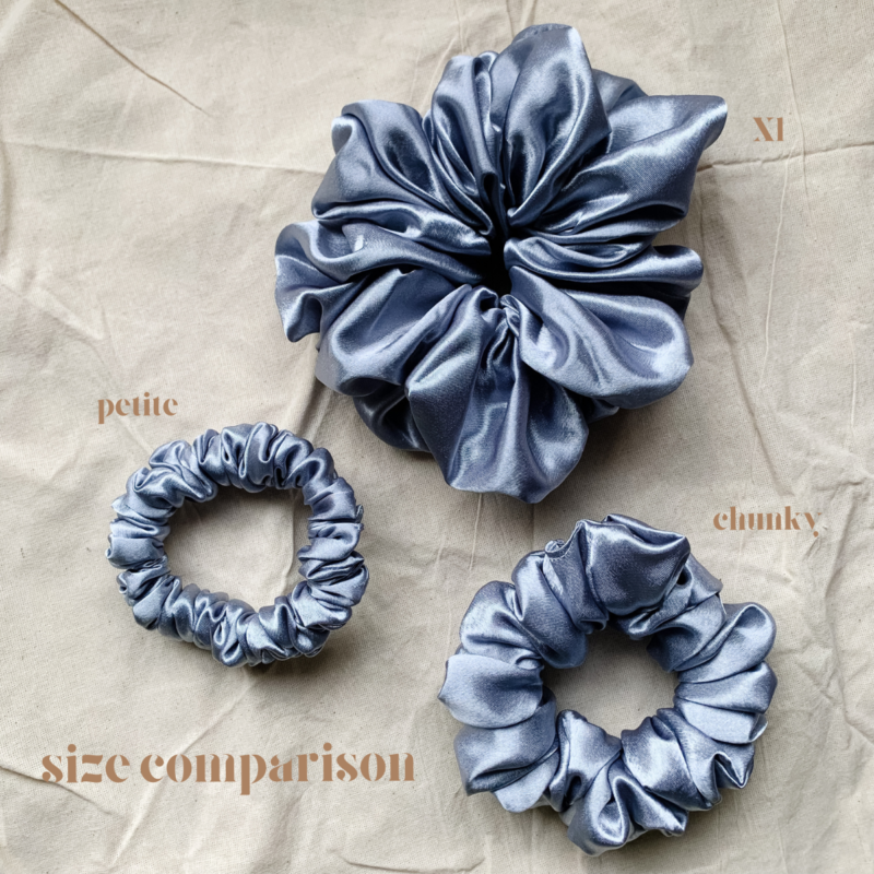 Moonlit Silver scrunchie comparison, showcasing three sizes: petite, chunky, and XL. The petite scrunchie offers a more delicate, subtle look, the chunky scrunchie adds bold volume, and the XL scrunchie, four times the size of the chunky, provides maximum volume and impact. All scrunchies are made from smooth, luxurious charmeuse silk for a glossy, elegant finish.