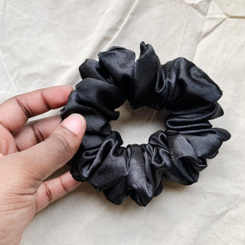 Noir black chunky scrunchie made from luxe charmeuse satin. Oversized design, approximately twice the size of a standard scrunchie, with a smooth, glossy finish that adds a touch of elegance and volume to any hairstyle.