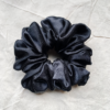 Noir XL scrunchie in black, made from luxurious charmeuse silk. Four times the size of the chunky scrunchie, this oversized scrunchie offers an extravagant, voluminous look with a smooth, glossy finish, perfect for making a bold statement or securing hair comfortably.