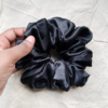 Noir XL scrunchie in black, made from luxurious charmeuse silk. Four times the size of the chunky scrunchie, this oversized scrunchie offers an extravagant, voluminous look with a smooth, glossy finish, perfect for making a bold statement or securing hair comfortably.
