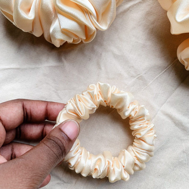 Oat milk cream petite scrunchie made from luxe charmeuse satin. Oversized design, approximately twice the size of a standard scrunchie, with a smooth, glossy finish that adds a touch of elegance to any hairstyle.