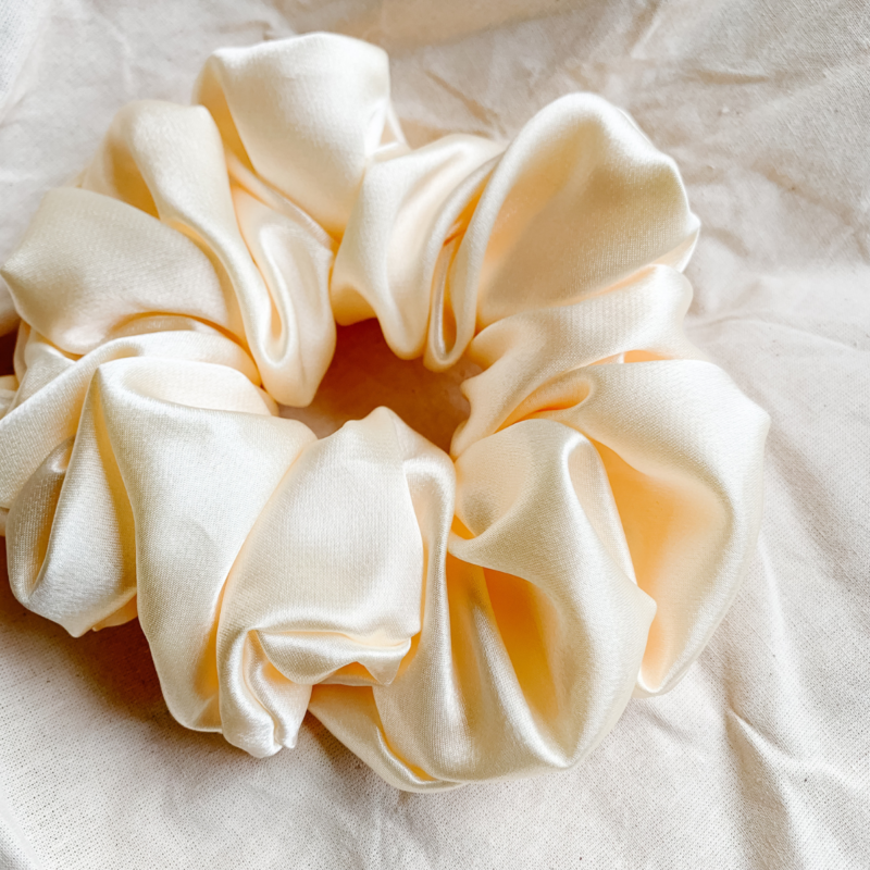 Oatmilk cream xl scrunchie made from luxe charmeuse satin. Oversized design, approximately twice the size of a standard scrunchie, with a smooth, glossy finish that adds a touch of elegance and volume to any hairstyle.