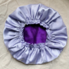 Purple Haze reversible silk bonnet in purple and lavender. Made from smooth charmeuse silk, this bonnet features a comfortable elastic band for a secure fit, offering a soft, luxurious touch for protecting hair while sleeping or resting.