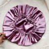 Rosé Glow reversible silk bonnet in metallic mauve. Made from smooth charmeuse silk, this bonnet features a comfortable elastic band for a secure fit, offering a soft, luxurious touch for protecting hair while sleeping or resting.