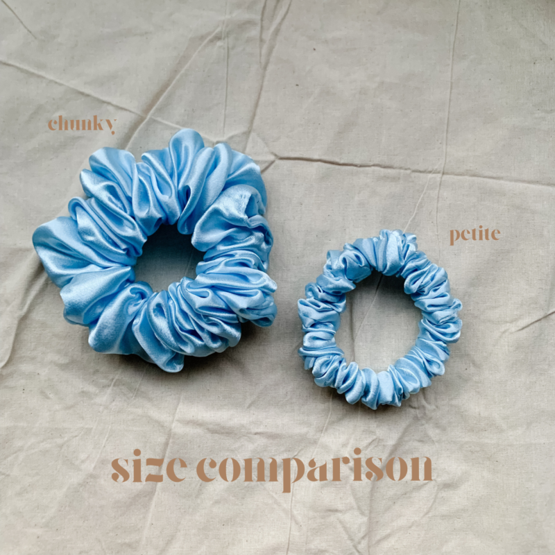 Blueberry scrunchie comparison in soft baby blue, showcasing two sizes: petite, chunky. The petite scrunchie offers a more delicate, subtle look, the chunky scrunchie adds bold volume. All scrunchies are made from smooth, luxurious charmeuse silk for a glossy, elegant finish.